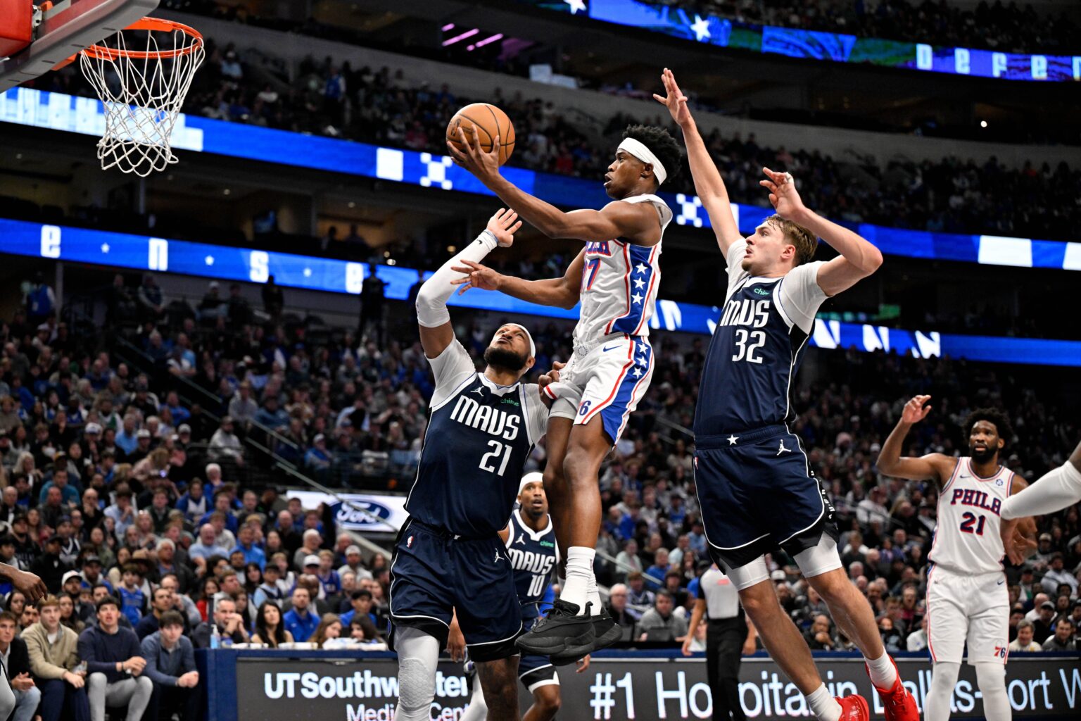 Jan 1, 2026; Dallas, Texas, USA; Philadelphia 76ers guard Vj Edgecombe (77) drives to the basket past Dallas Mavericks forward Daniel Gafford (21) and forward Cooper Flagg (32) during the second half at the American Airlines Center. Mandatory Credit: Jerome Miron-Imagn Images