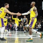 Feb 3, 2026; Brooklyn, New York, USA; Los Angeles Lakers guard Luka Doncic (77) greets forward LeBron James (23) during a timeout in the first quarter against the Brooklyn Nets at Barclays Center. Mandatory Credit: Wendell Cruz-Imagn Images