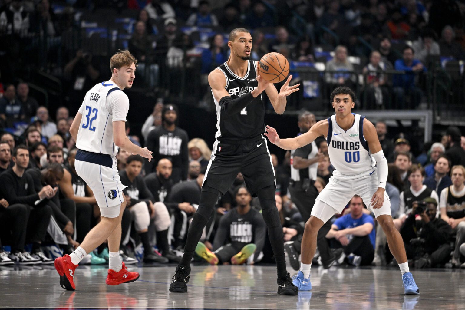 Feb 5, 2026; Dallas, Texas, USA; San Antonio Spurs forward Victor Wembanyama (1) passes the ball by Dallas Mavericks forward Cooper Flagg (32) and guard Max Christie (00) during the first quarter at the American Airlines Center. Mandatory Credit: Jerome Miron-Imagn Images