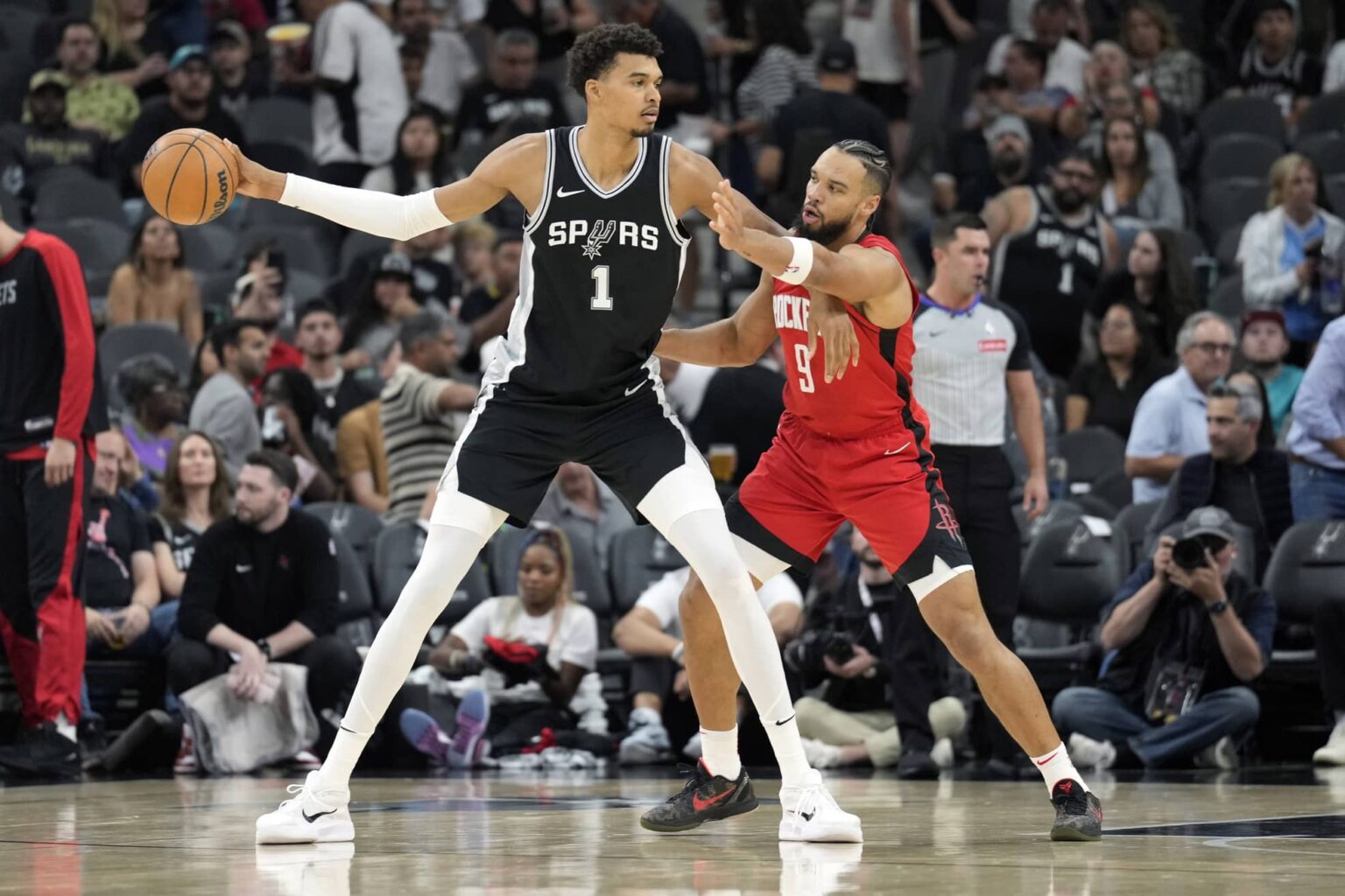 San Antonio Spurs center Victor Wembanyama (1) controls the ball while defended by Houston Rockets guard Dillon Brooks (9) during the first half at Frost Bank Center.