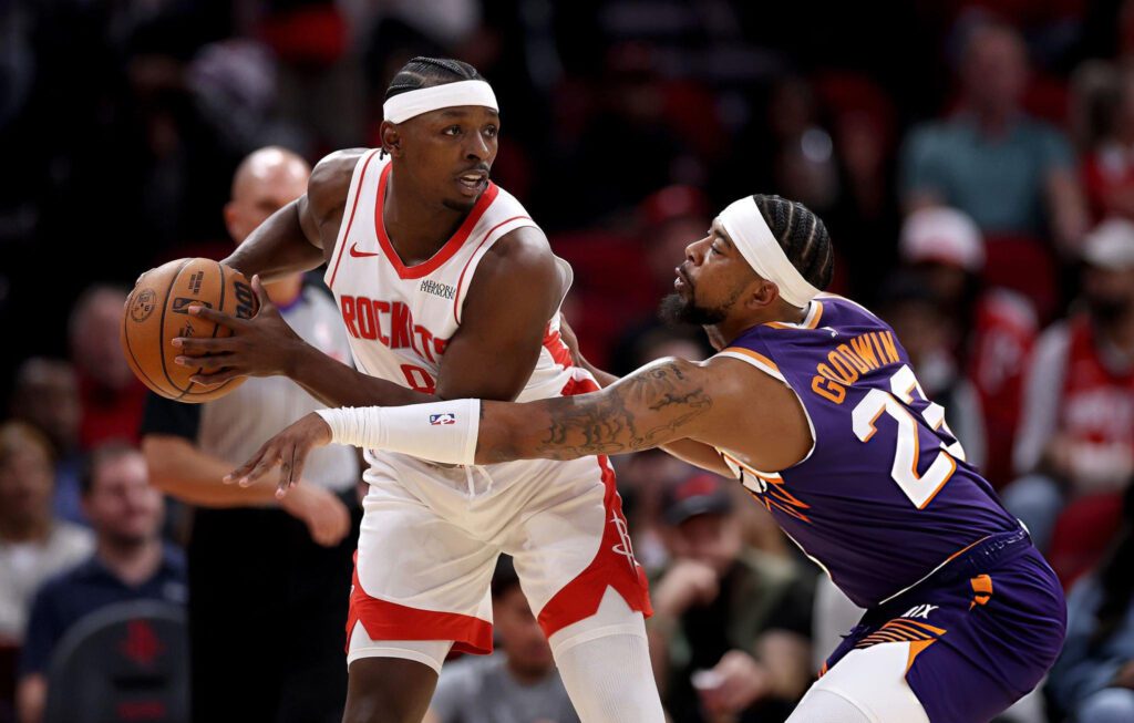 HOUSTON, TEXAS - DECEMBER 05: Jae'Sean Tate #8 of the Houston Rockets controls the ball against Jordan Goodwin #23 of the Phoenix Suns in the first half at Toyota Center on December 05, 2025 in Houston, Texas. (Photo by Tim Warner/Getty Images)