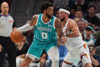 Apr 2, 2026; Charlotte, North Carolina, USA; Charlotte Hornets forward Miles Bridges (0) works the ball against Phoenix Suns guard Devin Booker (1)during the first quarter at Spectrum Center. Mandatory Credit: Jim Dedmon-Imagn Images