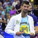 Novak Djokovic of Serbia reveals a t-shirt honoring the memory of friend and former NBA great, the late Kobe Bryant, during the trophy ceremony after his match against Daniil Medvedev (rear) in the men's singles final on day fourteen of the 2023 U.S. Open tennis tournament at USTA Billie Jean King National Tennis Center.