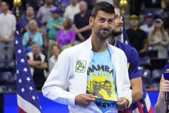 Novak Djokovic of Serbia reveals a t-shirt honoring the memory of friend and former NBA great, the late Kobe Bryant, during the trophy ceremony after his match against Daniil Medvedev (rear) in the men's singles final on day fourteen of the 2023 U.S. Open tennis tournament at USTA Billie Jean King National Tennis Center.