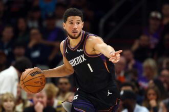 Apr 17, 2026; Phoenix, Arizona, USA; Phoenix Suns guard Devin Booker (1) against the Golden State Warriors during the first half in the play-in rounds of the 2026 NBA Playoffs at Mortgage Matchup Center. Mandatory Credit: Mark J. Rebilas-Imagn Images